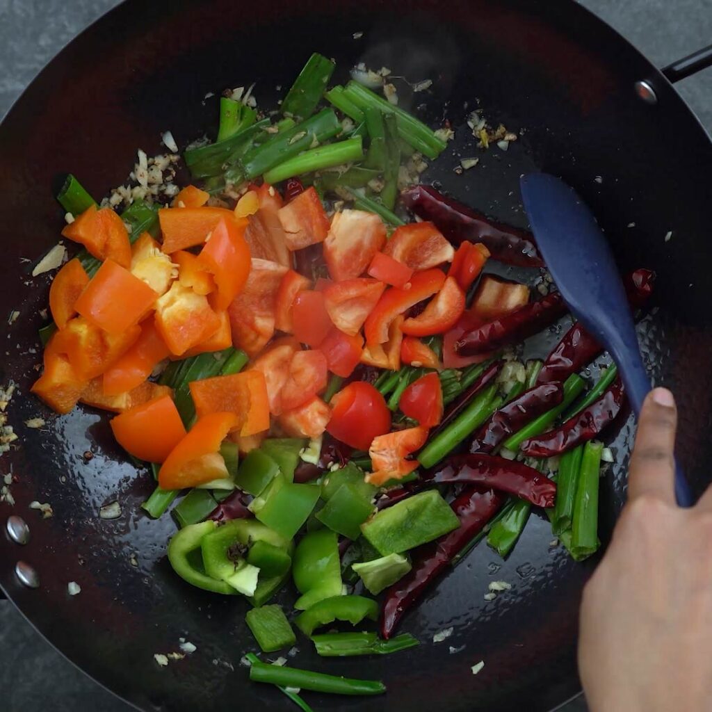 stir-frying bell peppers in a wok