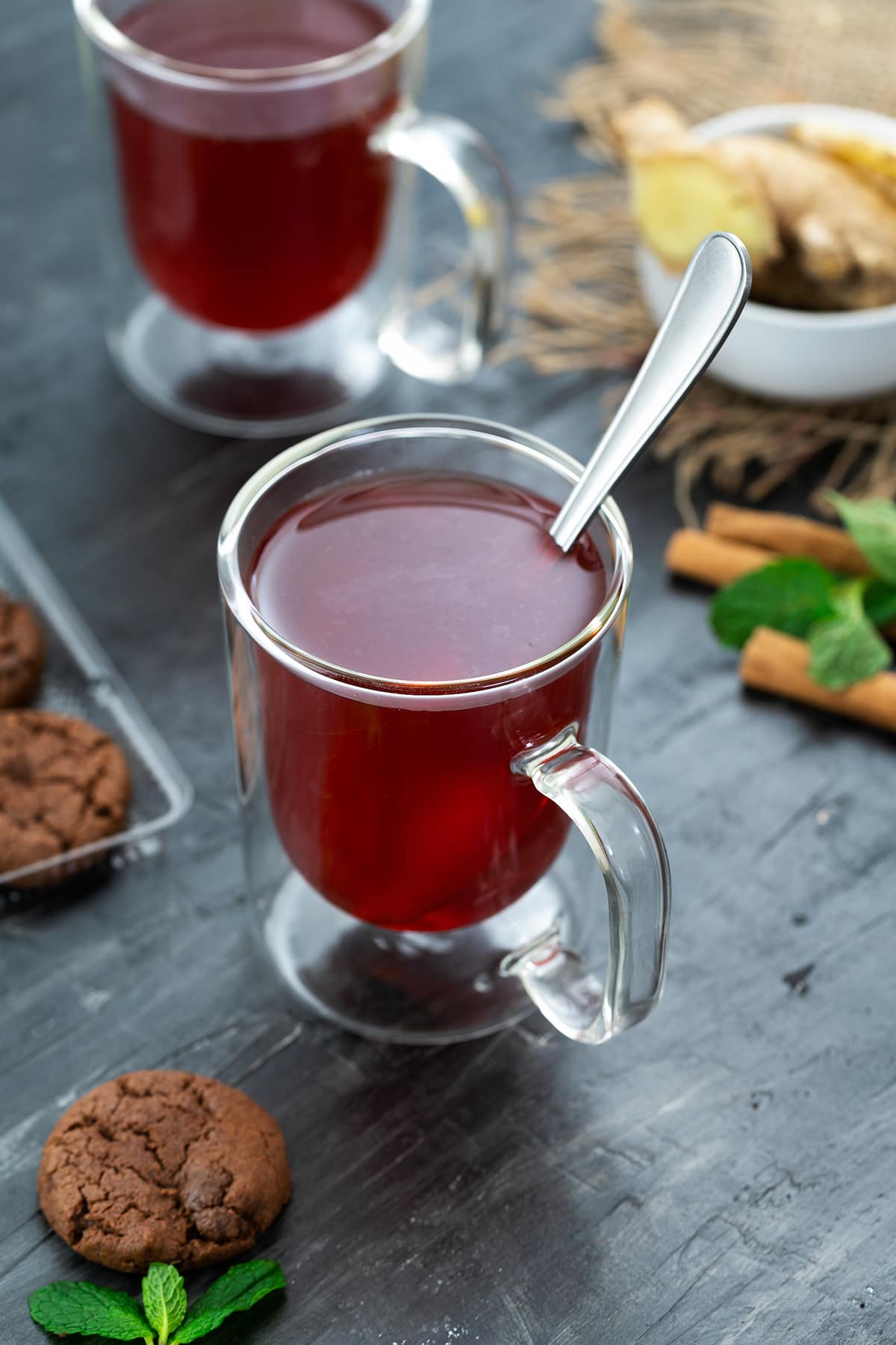 Ginger Tea served in a mug with cinnamon and mint leaves nearby.