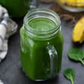 Green Smoothie served in a mug with spinach leaves placed nearby.