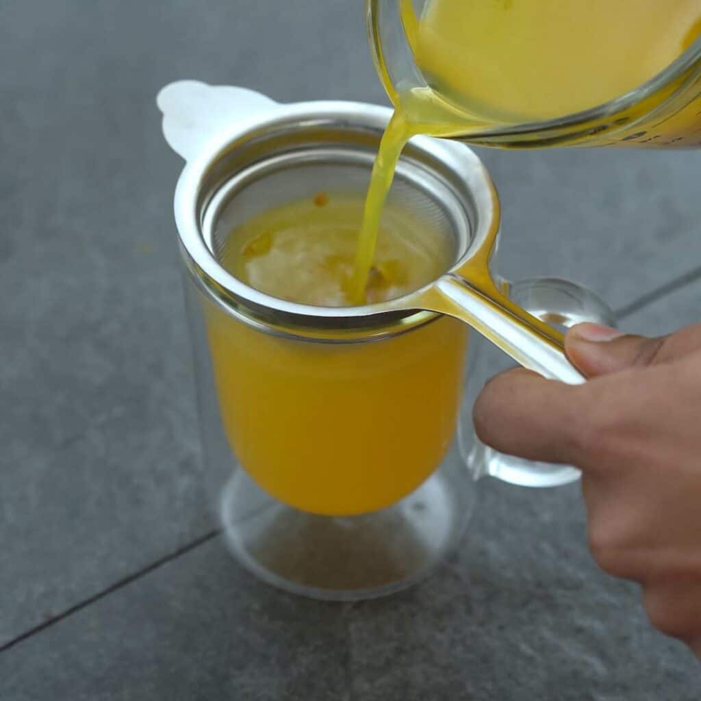 Filtering the Turmeric Tea into serving glass.