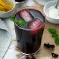 Hibiscus tea (Agua de Jamaica) served in a glass with ice cubes and mint leaves.