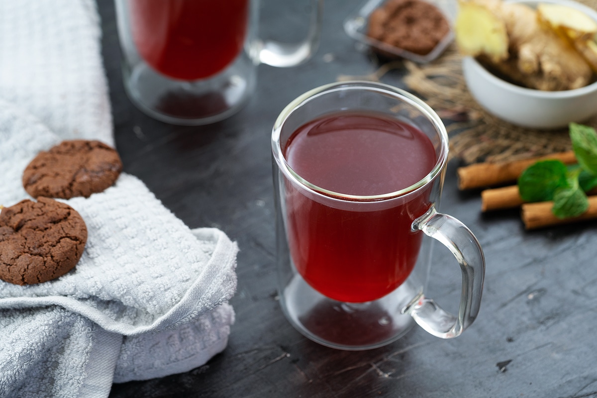 Ginger Tea served in a mug with cinnamon and mint leaves nearby.