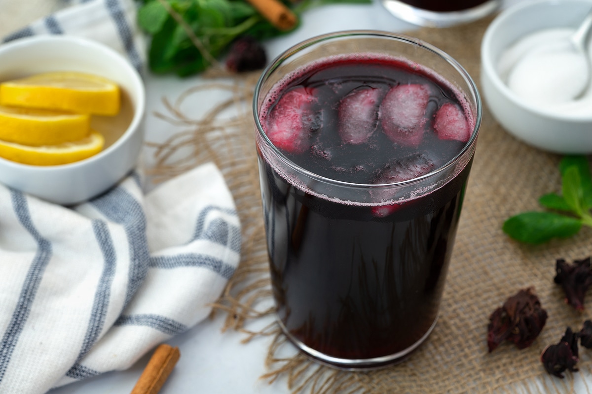 Hibiscus tea (Agua de Jamaica) served in a glass with ice cubes and mint leaves.