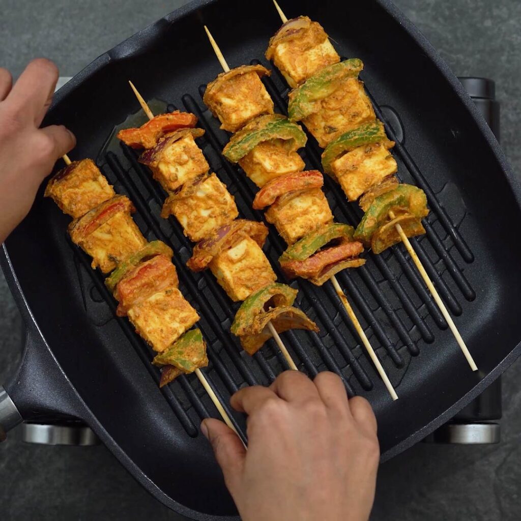 paneer and veggies are being grilled in a a grilling pan