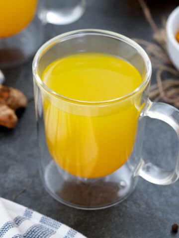 Turmeric Tea served in a mug with fresh turmeric placed nearby.
