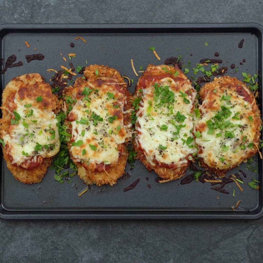 Chicken Parmigiana or chicken parmesan in a tray garnished with parsley