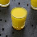 Ginger Shots served in a shots glass with peppercorns scattered around.