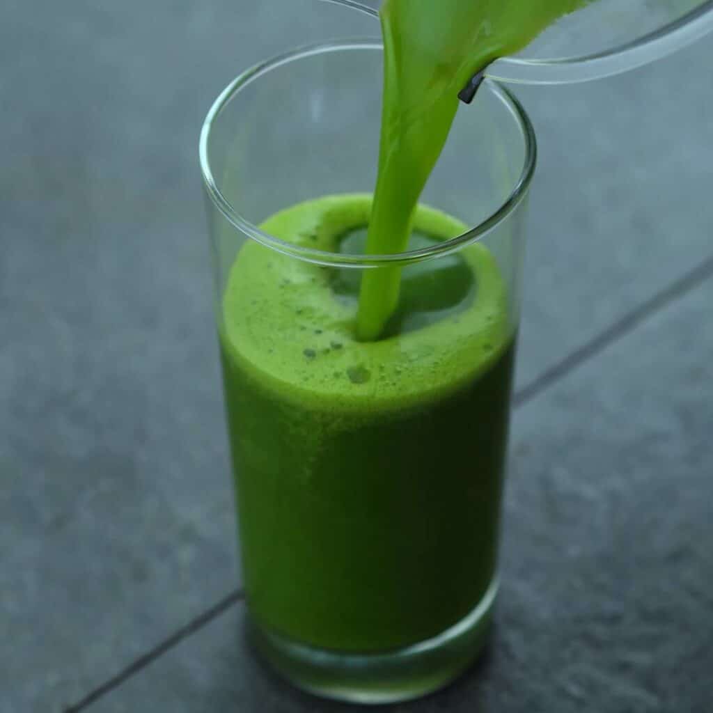 Pouring the green juice into a serving glass.