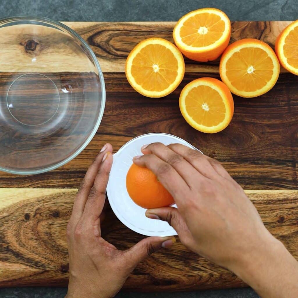 Squeezing the oranges to extract juice.