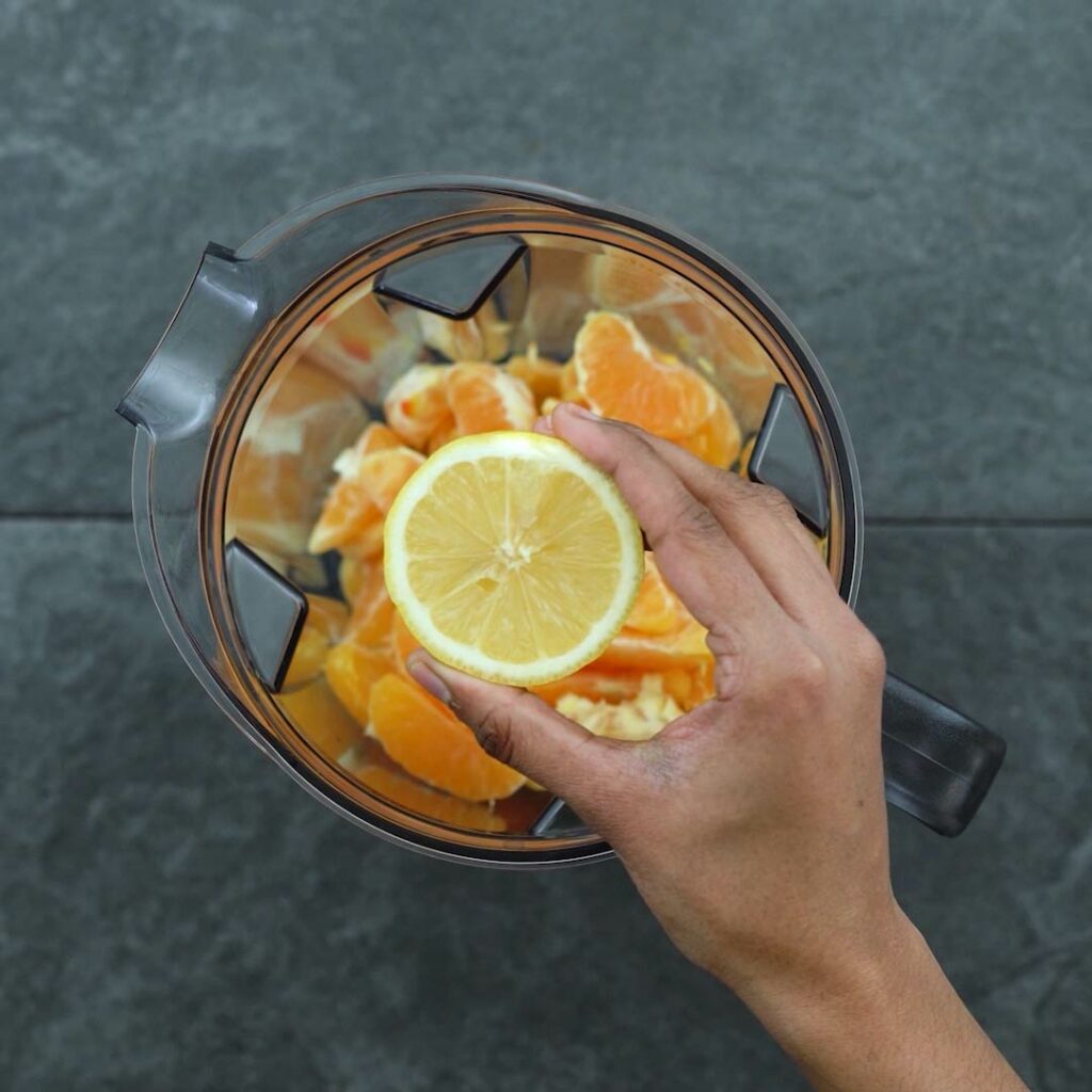 Adding lemon juice to the oranges in blender.