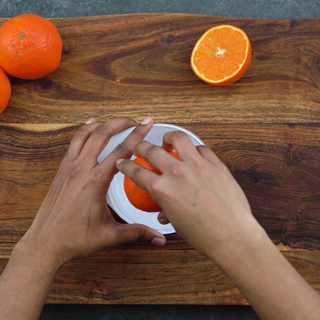 Squeezing Orange in a handheld juicer.