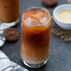 Thai Iced Tea served in a tall glass with condensed milk and cookies placed near by.