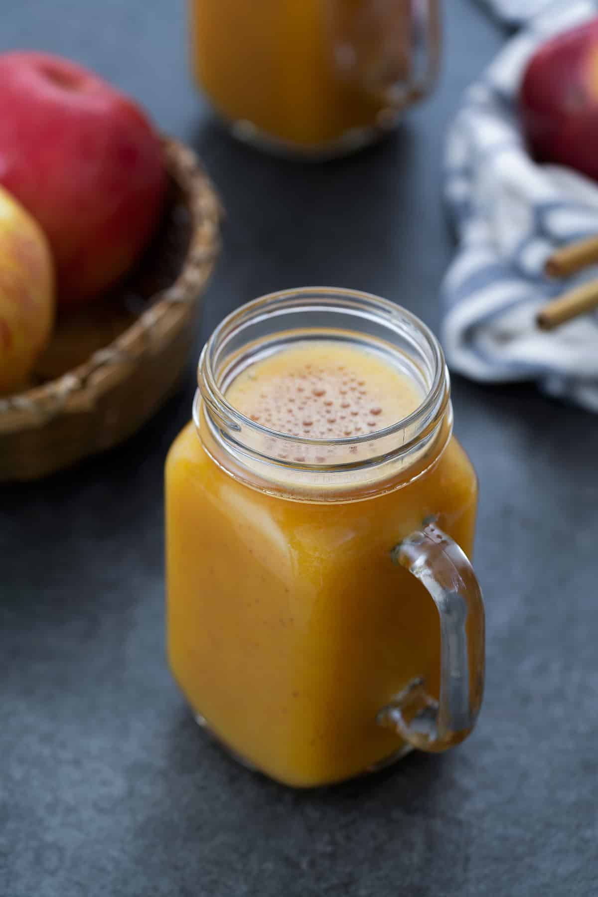 Apple Juice served in a mug with apples placed nearby.
