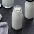 Buttermilk and buttermilk substitute in a milk bottle with kitchen towel placed nearby.