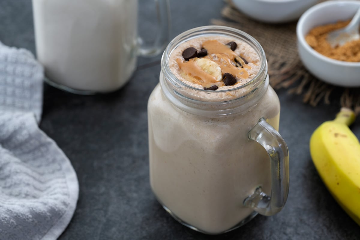 Peanut Butter Banana Smoothie served in a mug topped with chocolate chip, banana, and peanut butter.