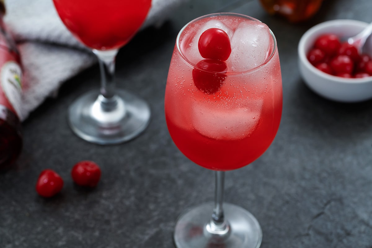 Shirley Temple Drink served in a wine glass topped with cherries.