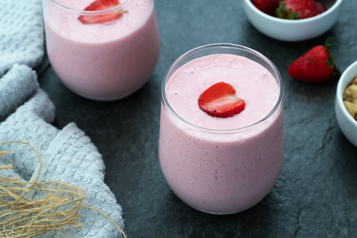 Fresh Strawberry Smoothie Served in a glass with strawberries placed nearby.
