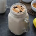 Peanut Butter Banana Smoothie served in a mug topped with chocolate chip, banana, and peanut butter.
