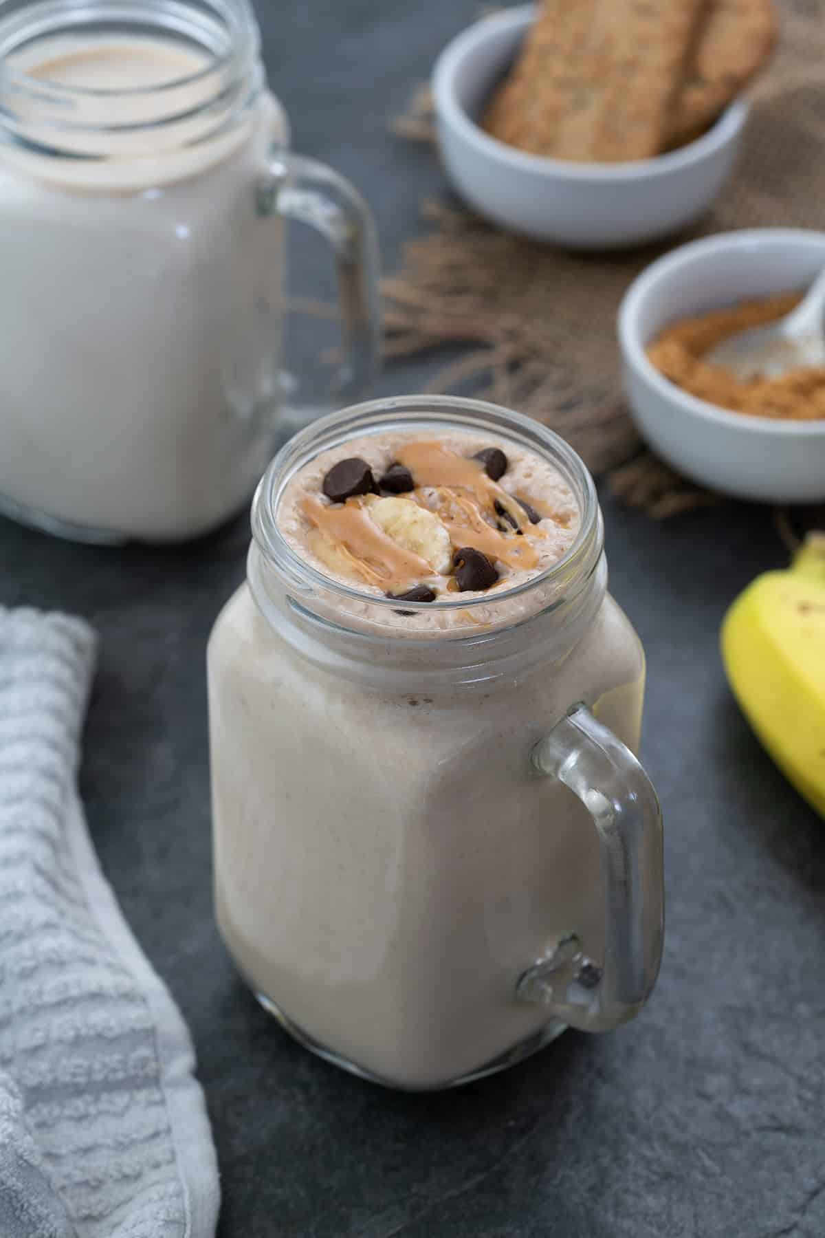 Peanut Butter Banana Smoothie served in a mug topped with chocolate chip, banana, and peanut butter.