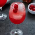 Shirley Temple Drink served in a wine glass topped with cherries.