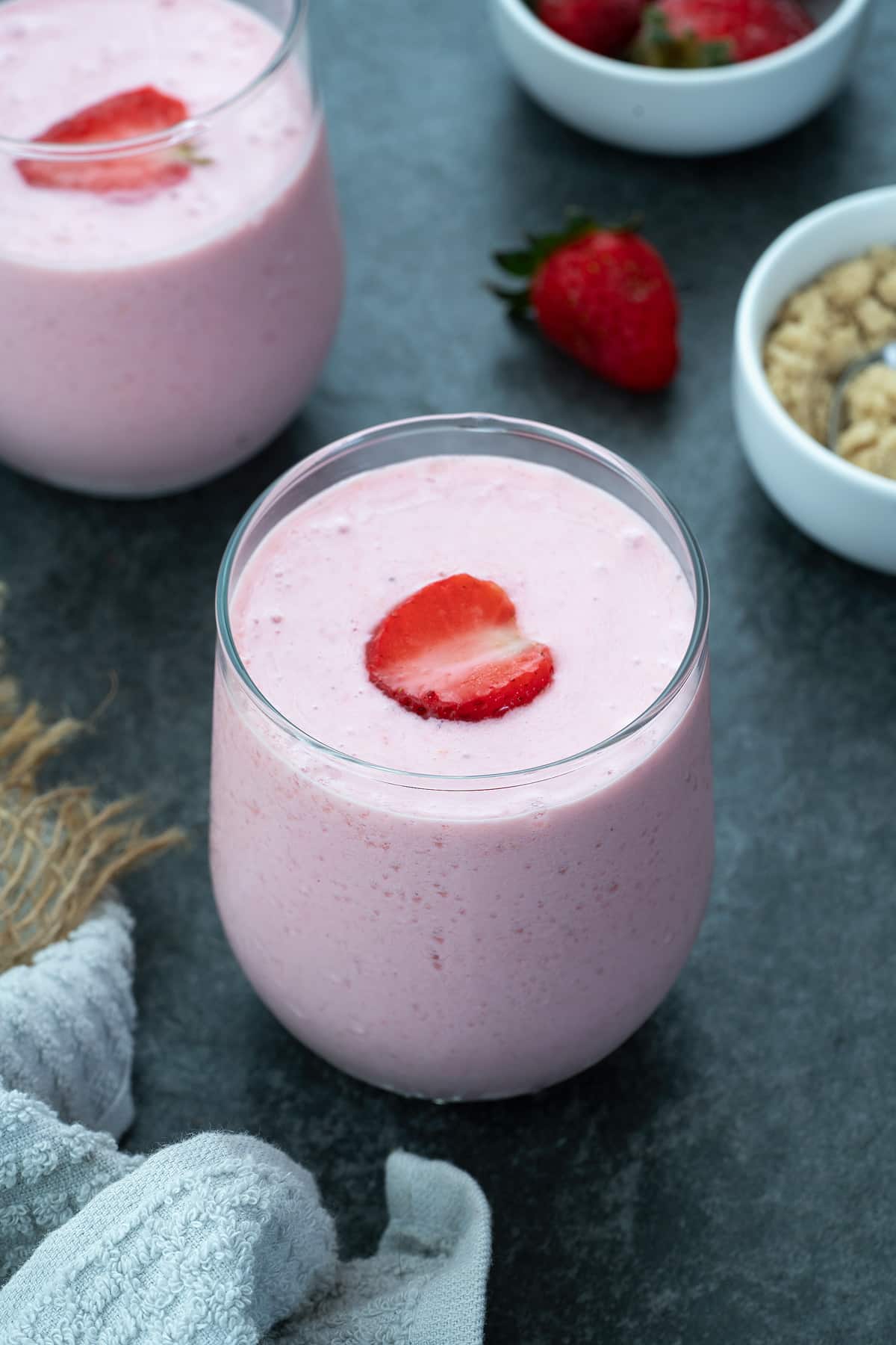Fresh Strawberry Smoothie Served in a glass with strawberries placed nearby.