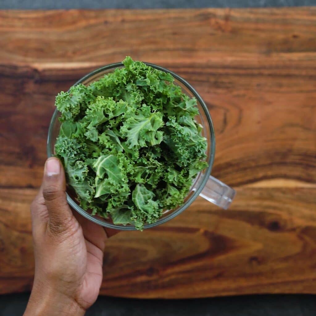 Adding kale leaves to blender jar.