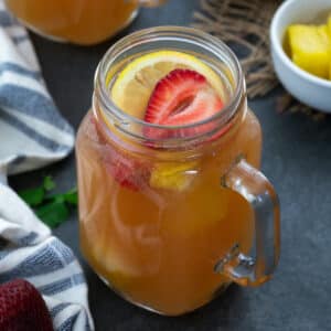 Fruit punch (party punch) served in glass mug topped with strawberries and lemon slice.