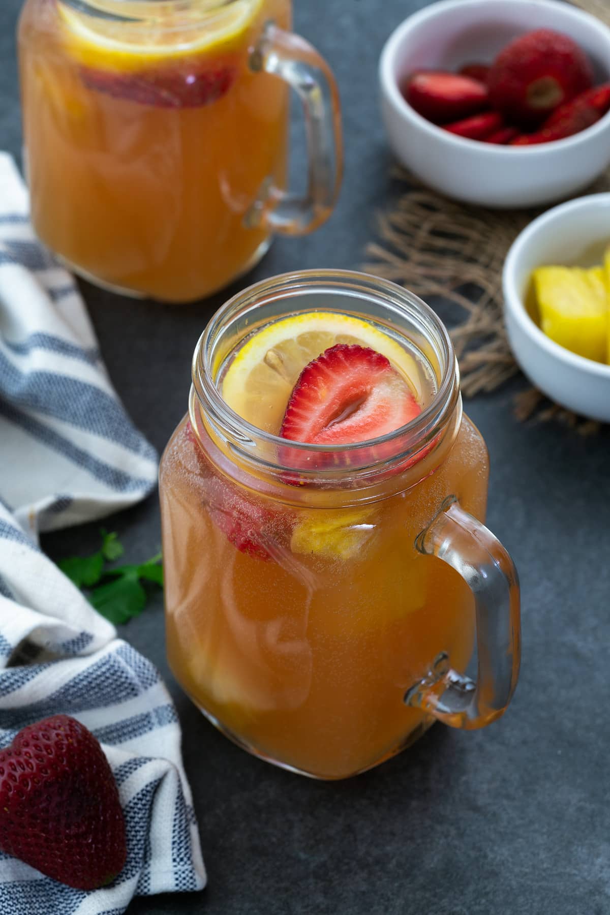 Fruit punch (party punch) served in glass mug topped with strawberries and lemon slice.