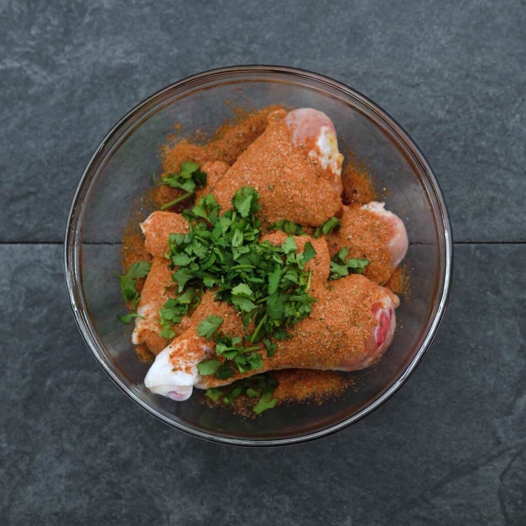 Chicken Drumstick and seasoning mix and herbs in a bowl
