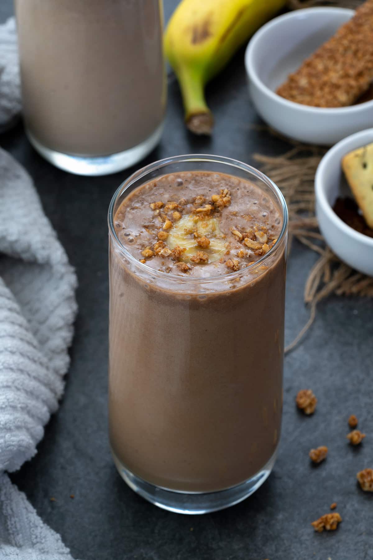 Protein Smoothie served in a glass topped with banana and granola.