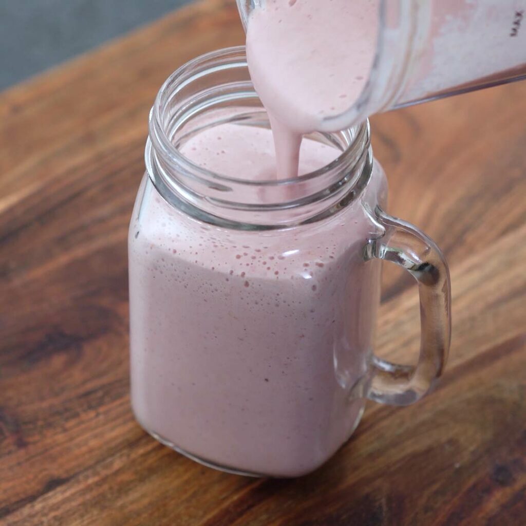 Pouring Greek Yogurt Smoothie into a serving glass.