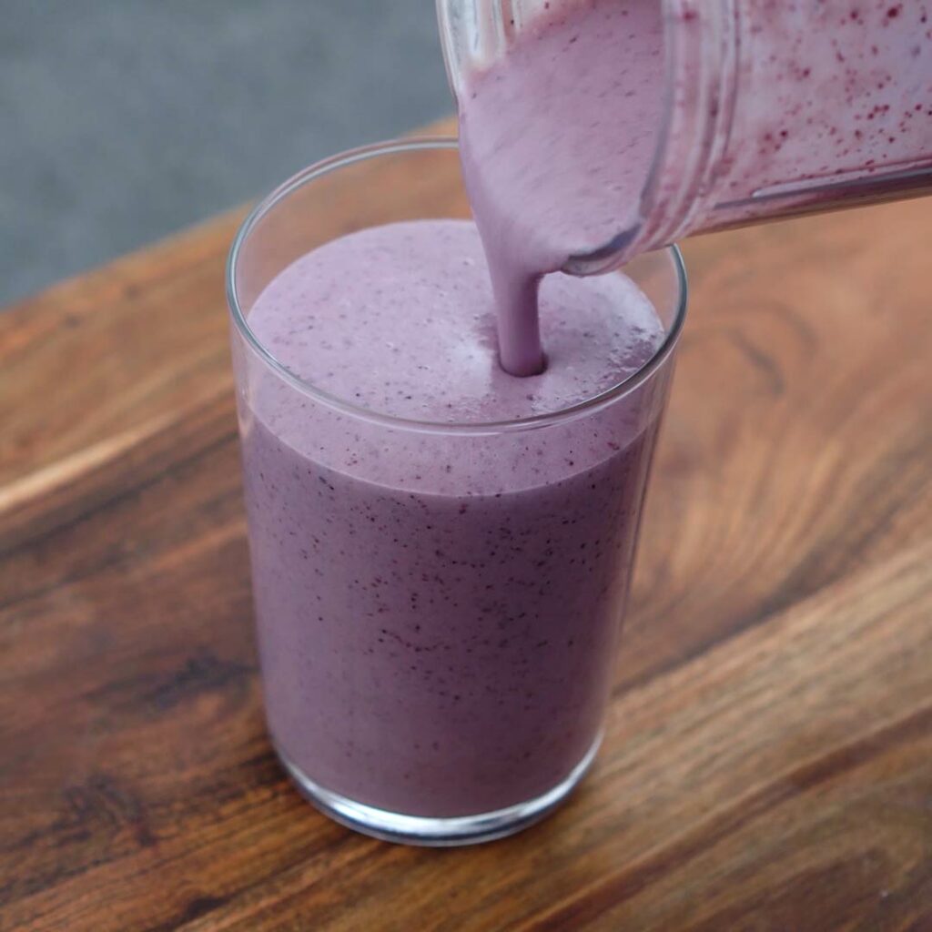 Pouring Blueberry Smoothie into a serving glass.