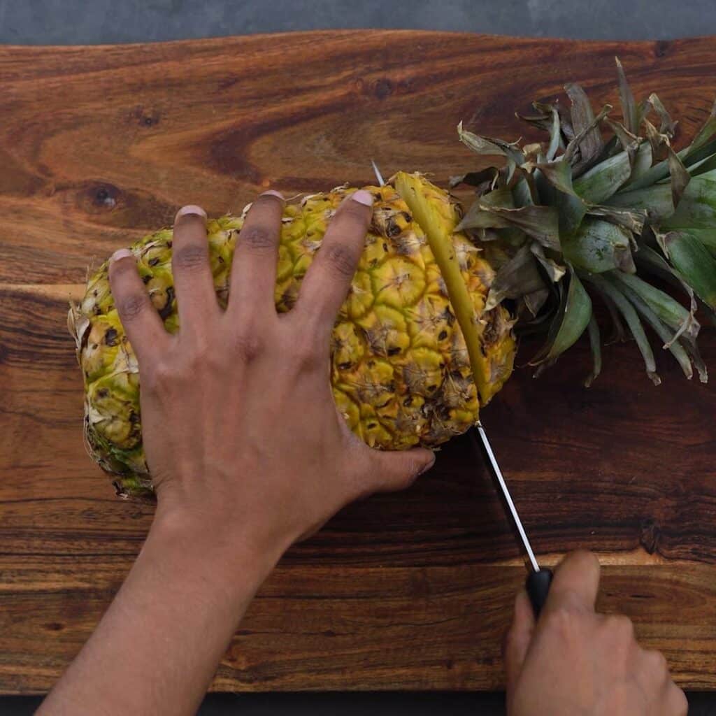 Cutting the crown part of the pineapple.
