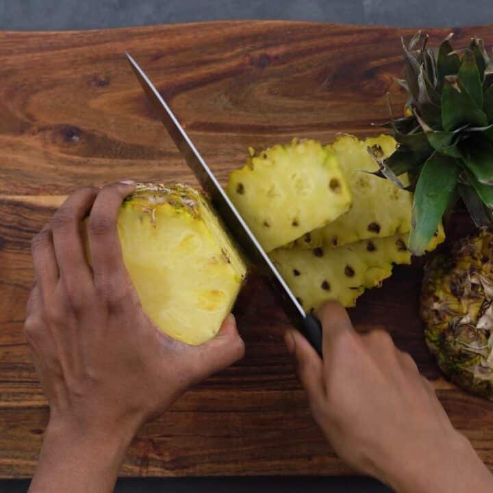 Slicing the peel of the pineapple.