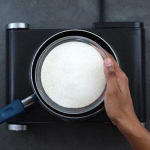 Adding sugar to a saucepan.