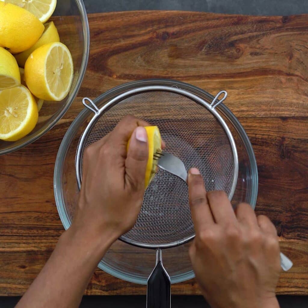 Squeezing the lemon juice using fork.