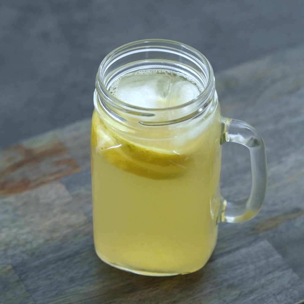Lemonade served in cup with lemon slices and ice cubes.