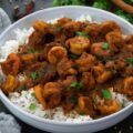 Shrimp Vindaloo Curry in a white bowl with rice on a table