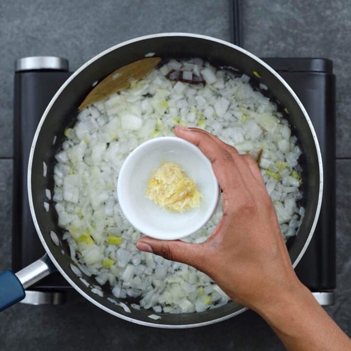 Adding grated ginger garlic to onion
