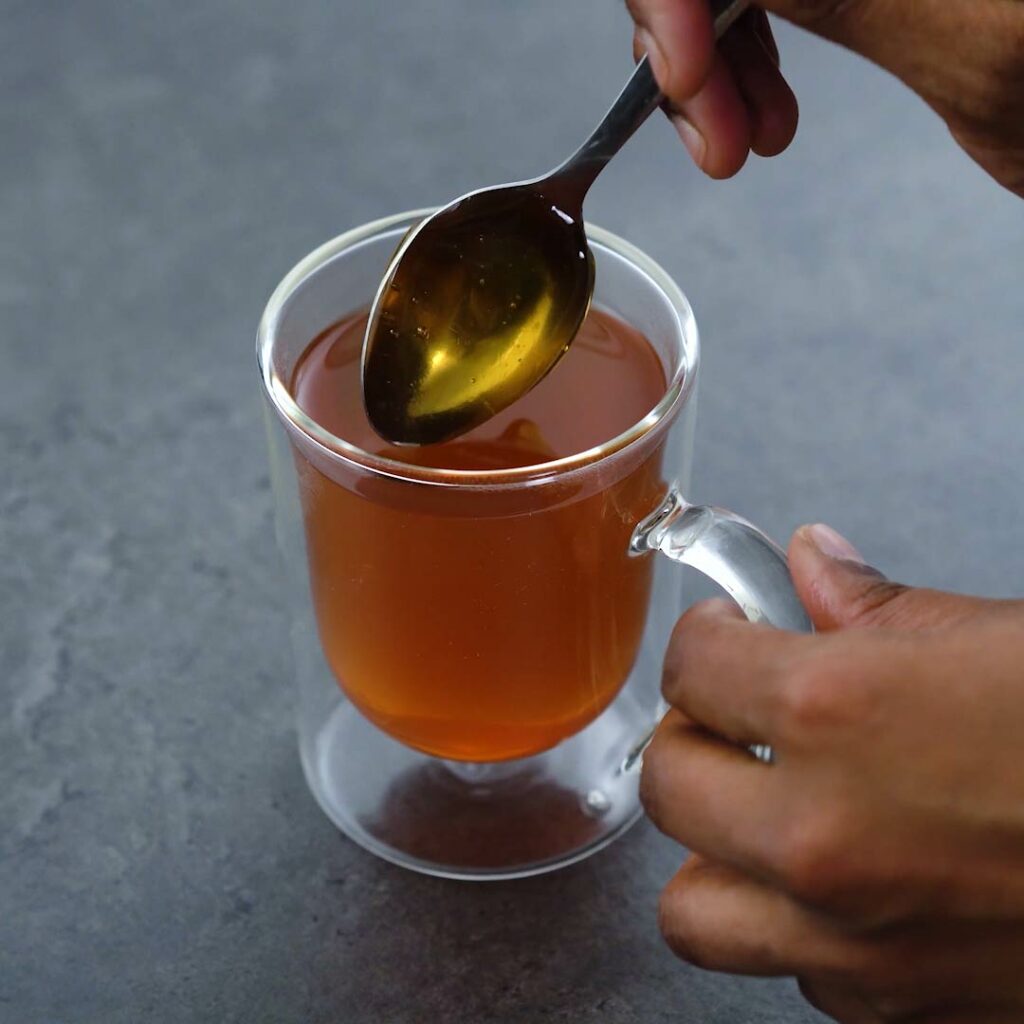 Adding honey to lemon tea.