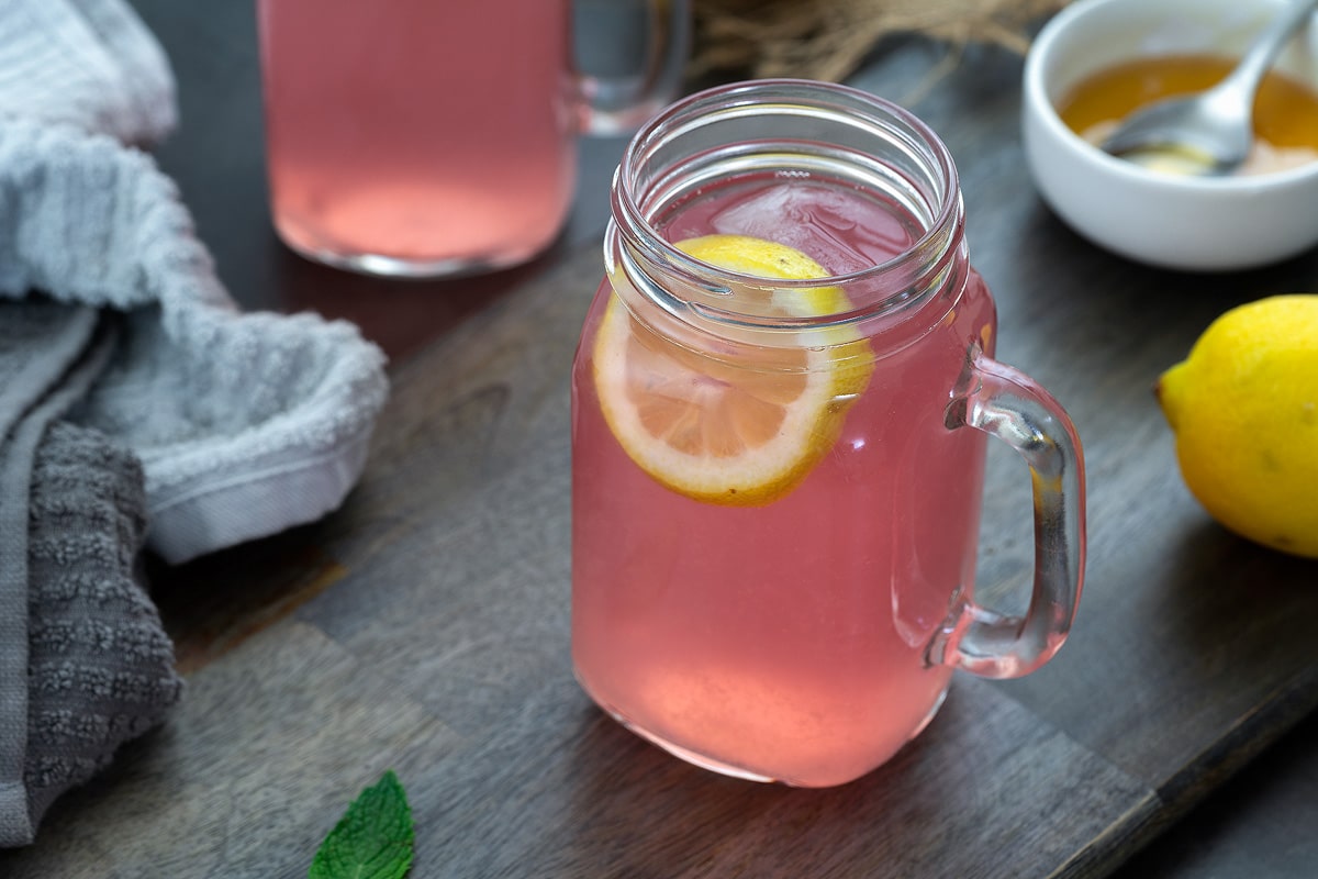 Pink Lemonade in a serving mug. Honey and lemon placed nearby.