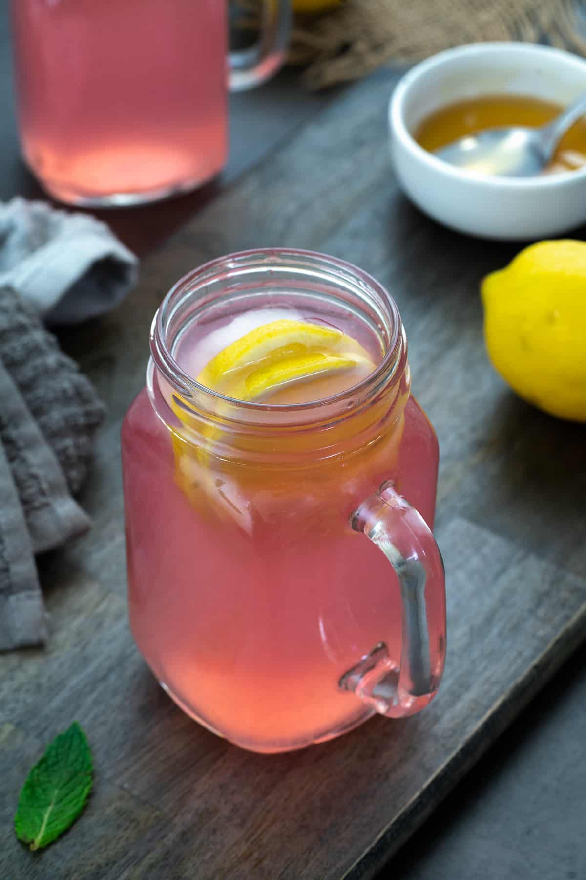 Pink Lemonade in a serving mug. Honey and lemon placed nearby.
