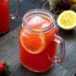 Strawberry Lemonade in a glass mug placed on a table with lemon and strawberry nearby.