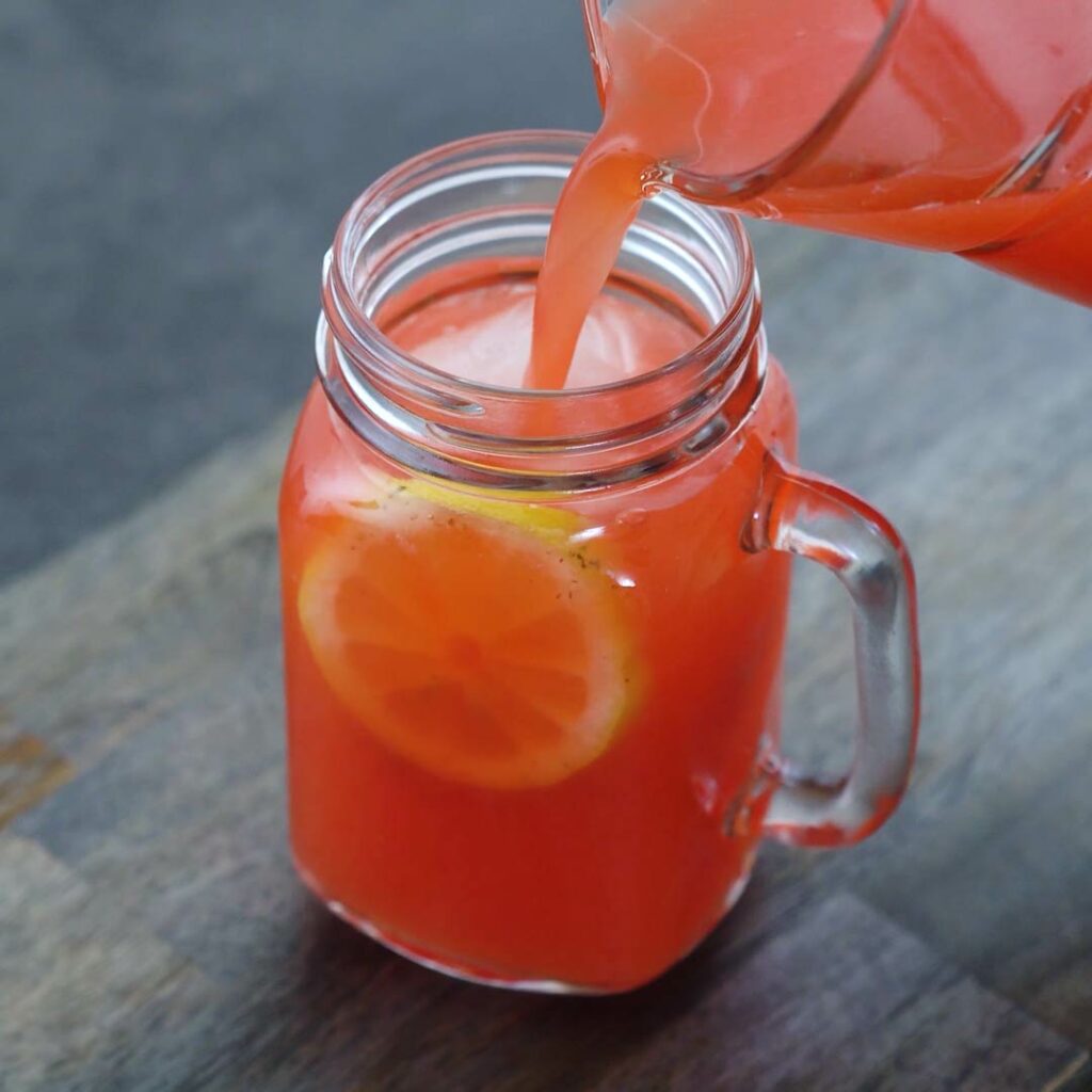Pouring Strawberry Lemonade in a serving mug.