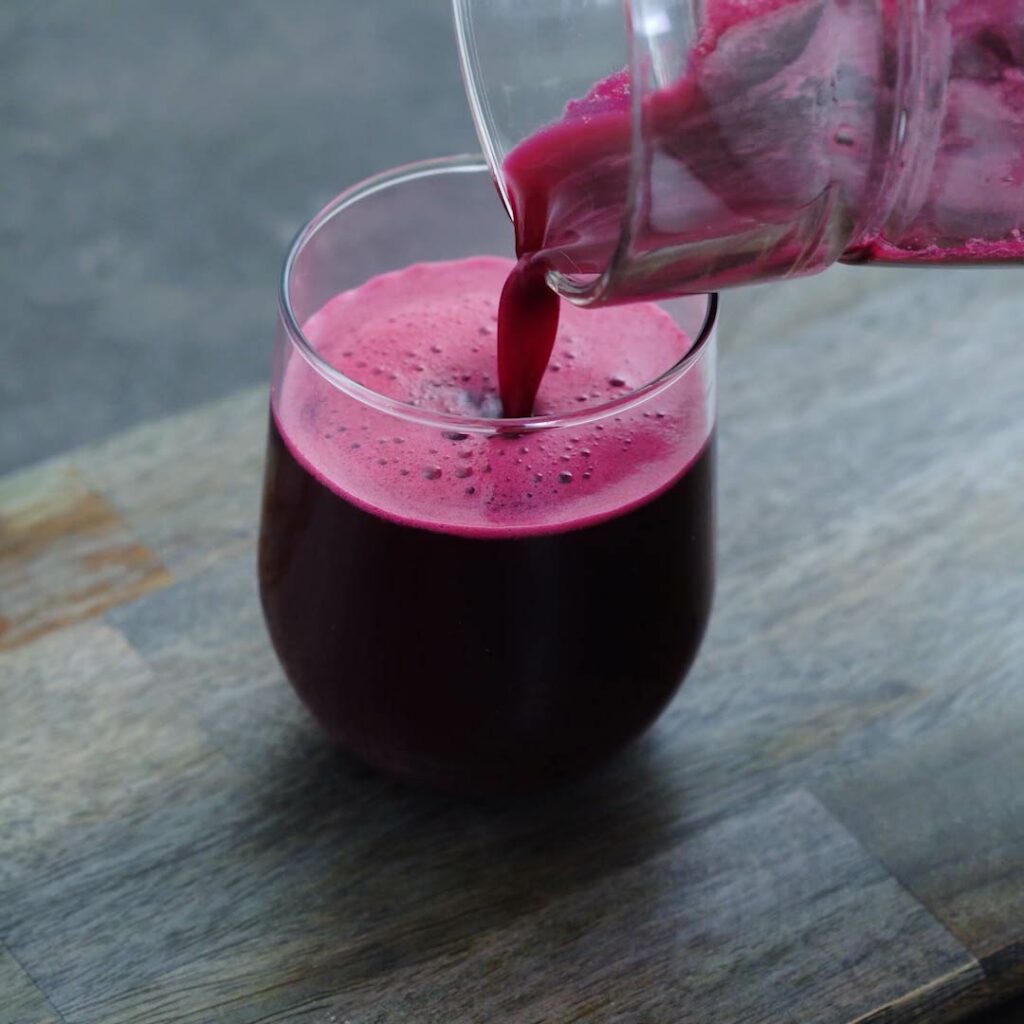 Pouring Beetroot juice into a serving glass.