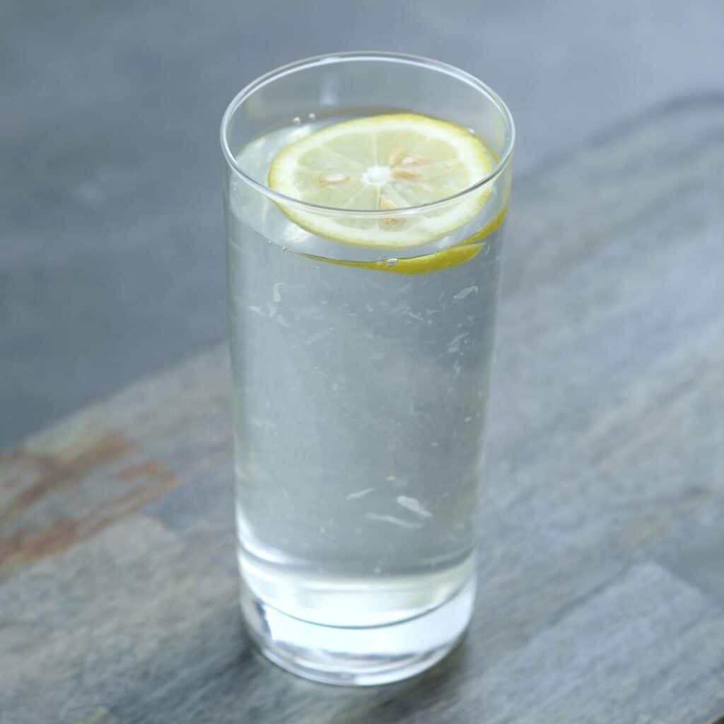 Lemon Water in a serving glass with lemon slice.