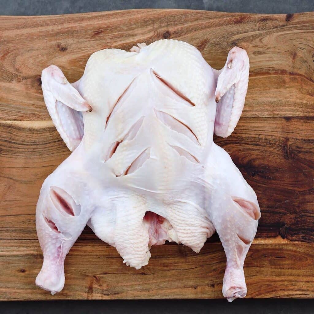 Slit whole chicken on a cutting board