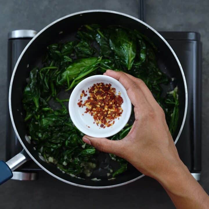Seasoning the spinach with chili flakes
