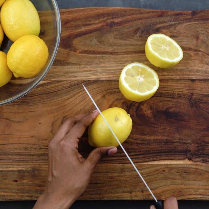 Cutting the lemons in half with a knife.