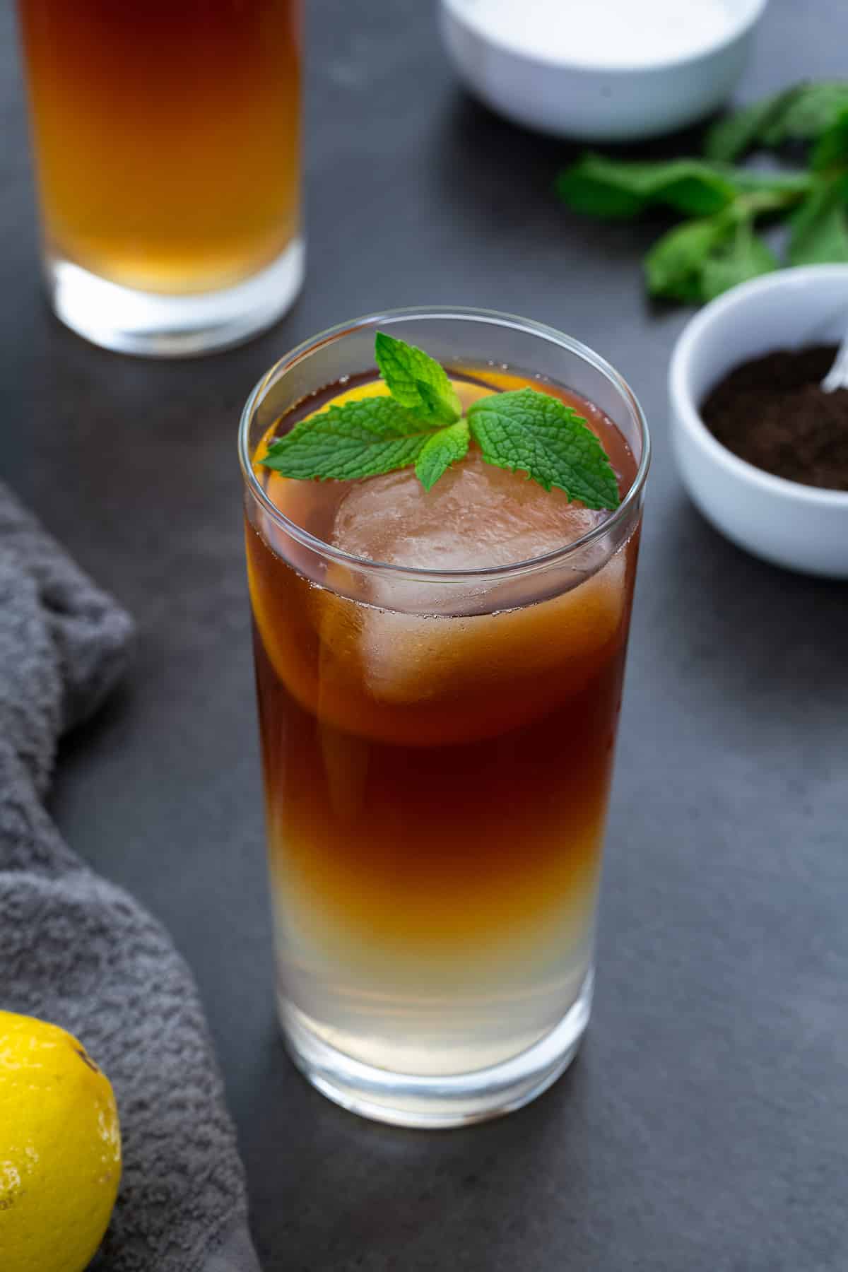 Arnold Palmer drink in a glass placed on a grey table with few ingredients around.